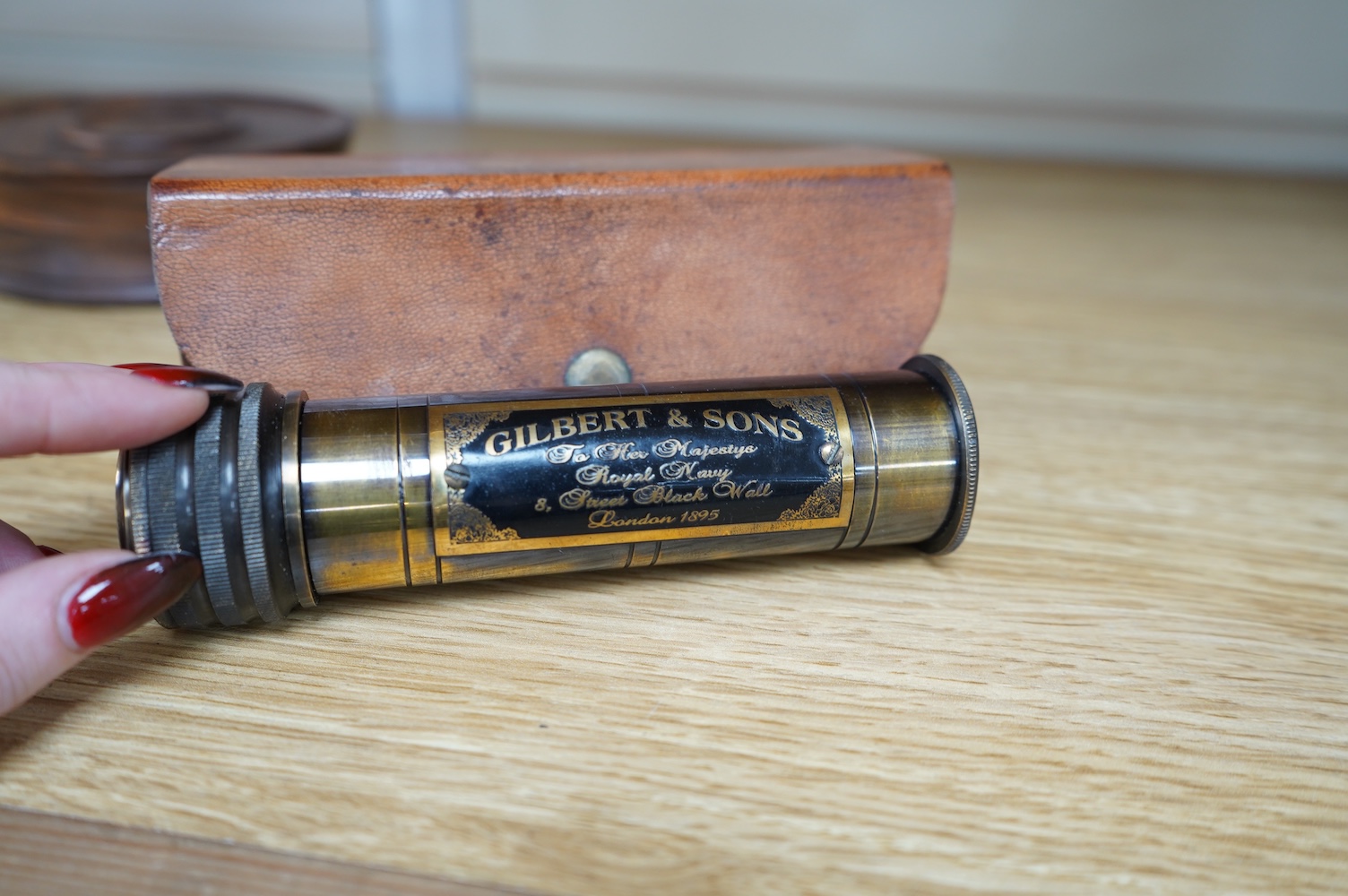 A reproduction 19th century style brass kaleidoscope with panel reading; ‘Gilbert & Sons To Her Majesty’s Royal Navy, 8 Street Black Wall, London 1895’, 13.5cm long, in a leather case, together with a wood cased brass so